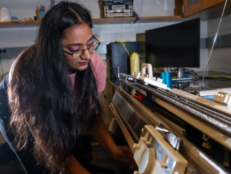 Former Matsumoto Group member Krishma Singal operates a knitting machine used to create fabric samples for a previous study. Singal recently graduated from Georgia Tech with her Ph.D. (Photo Credit: Allison Carter)